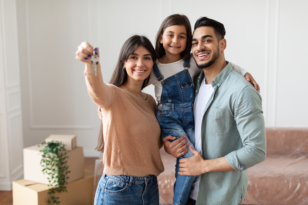 Portrait Of Happy Young Family Showing Key, Cheerful Parents Hugging Little Kid, Holding Daughter On Hands Portrait Of Happy Young Family Showing Key, Cheerful Parents Hugging Little Kid, Holding Daughter On Hands